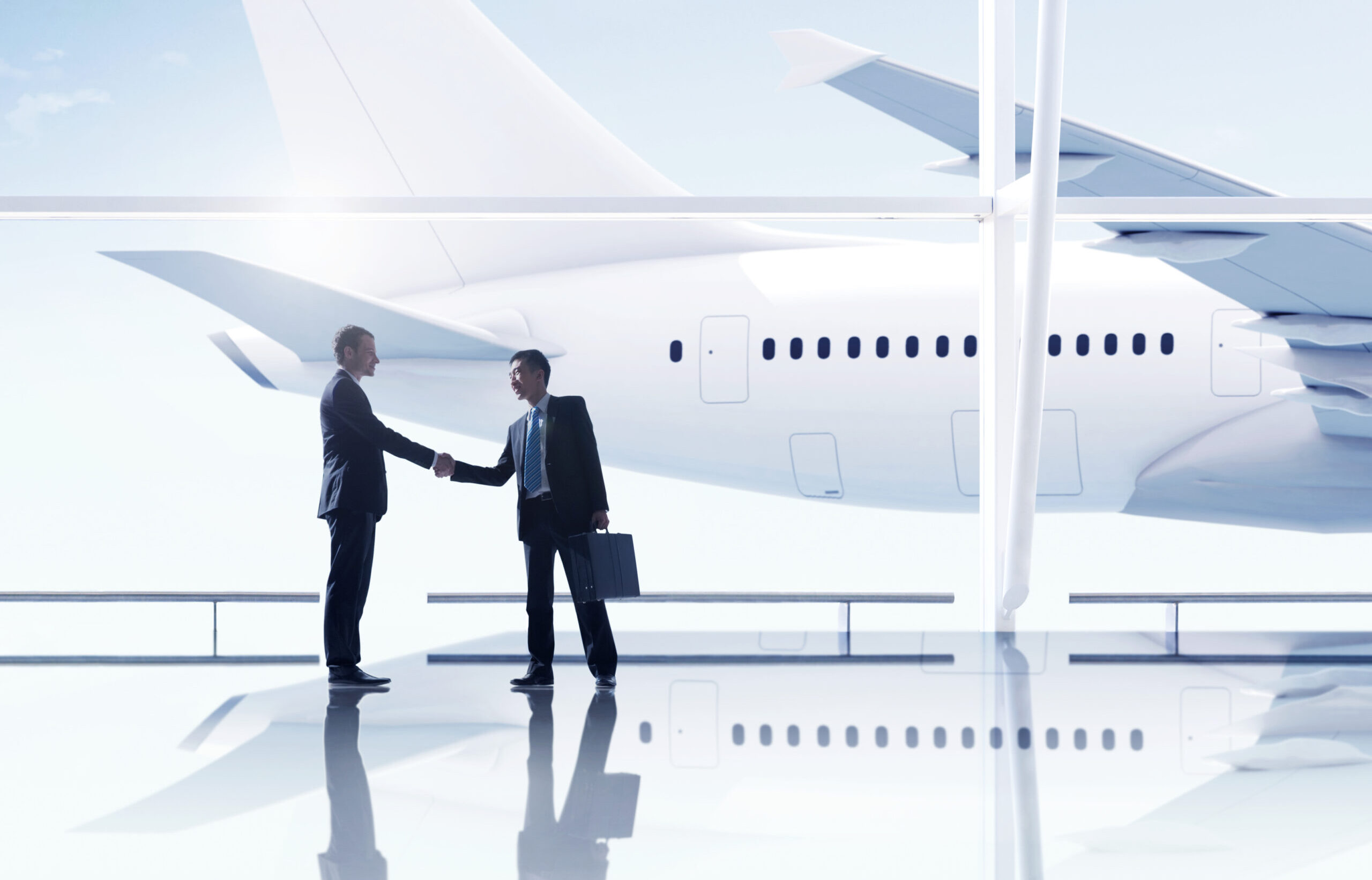 Western and asian businessmen handshake airport meeting